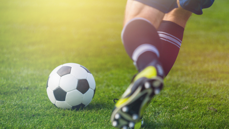 A male footballer about to kick a ball.