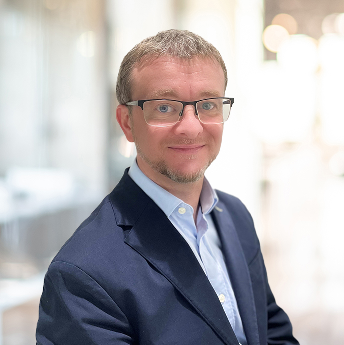 A smartly-dressed, blue-eyed man with glasses, short, greying, blonde hair and a neatly-trimmed beard.